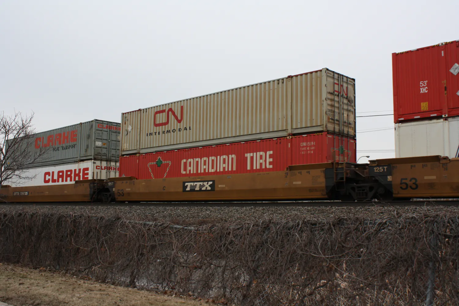 Double-stacked CN Intermodal and Canadian Tire shipping containers riding a TTX well car on a Canadian National freight train